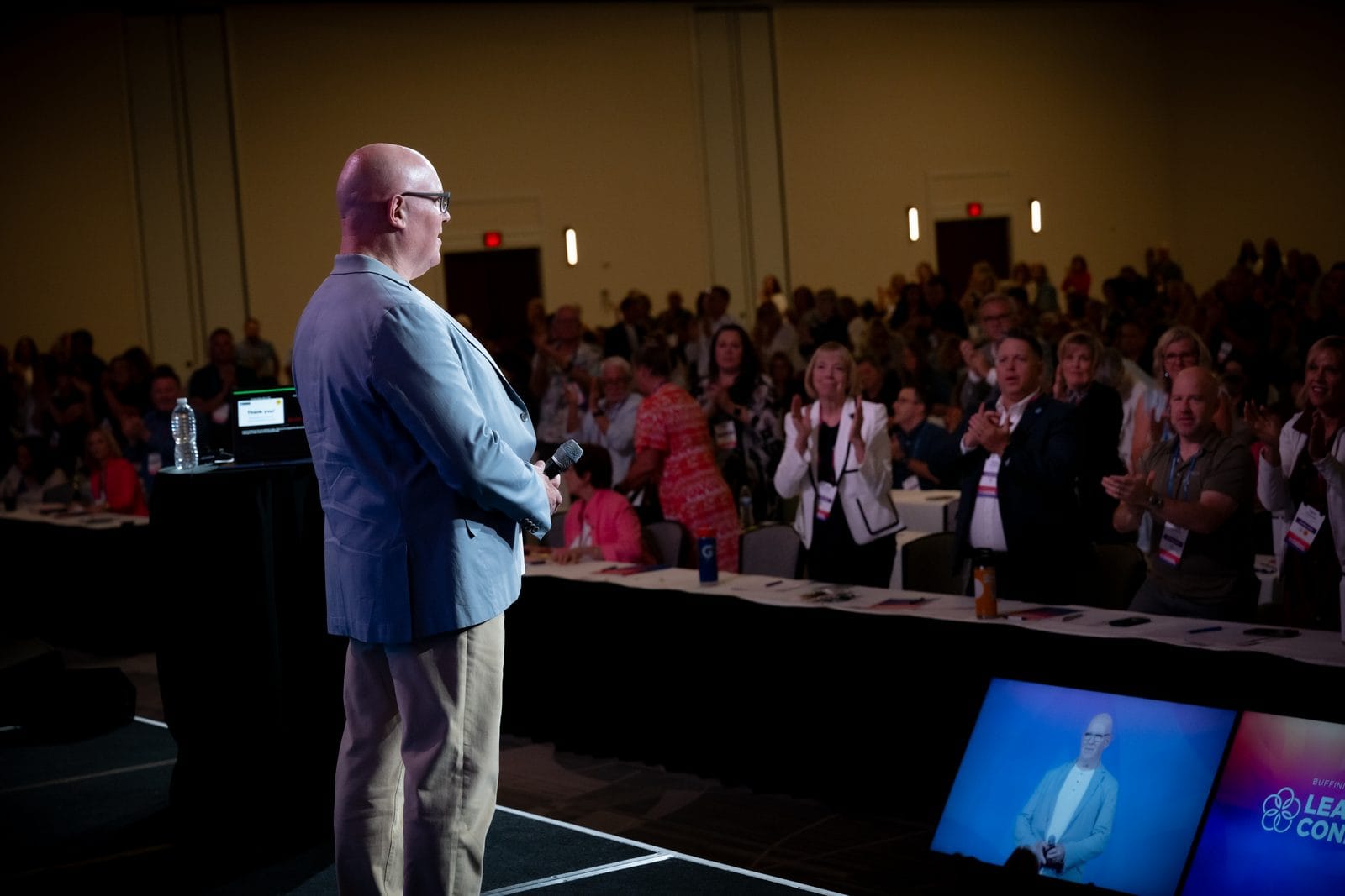 Julian Treasure on stage at a leadership conference as the audience stands to applaud
