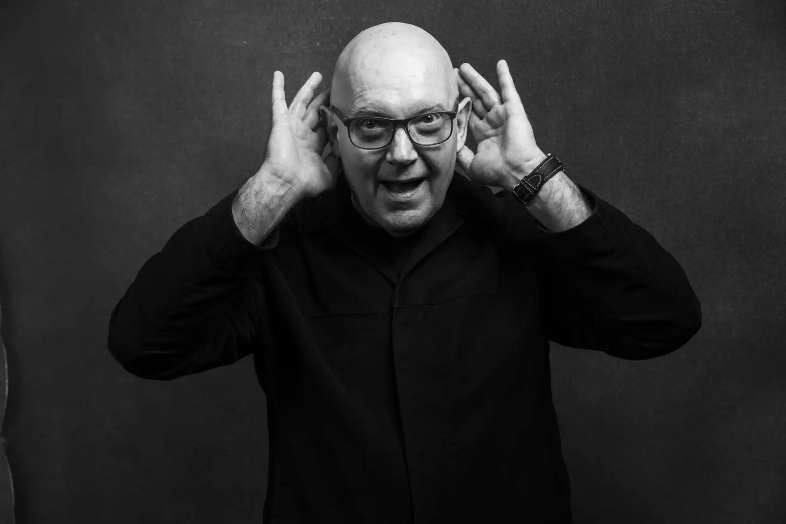Julian Treasure cupping both hands to his ears, in black and white