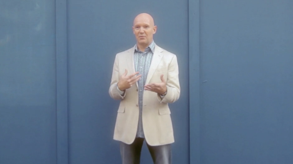 Julian Treasure speaking to camera in a cream jacket against a blue wall